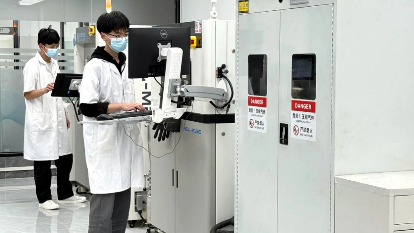 KC Dental Lab technicians inspecting a case beside production and quality-control equipment